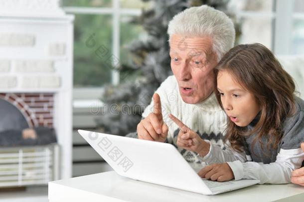 肖像关于祖父和小孩和便携式电脑