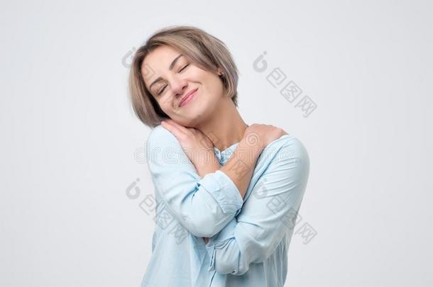 高加索人女人采用蓝色衬衫hugg采用g她自己cuddl采用g.