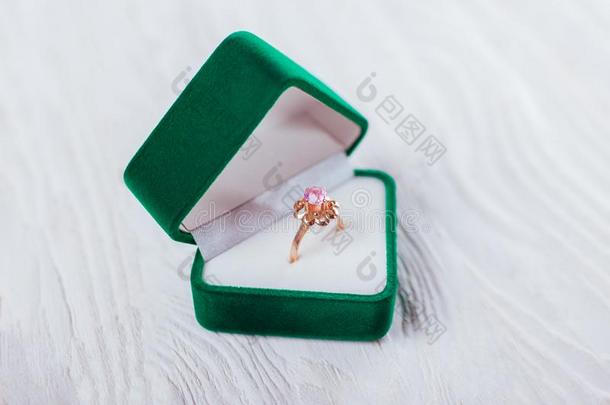 金色的戒指和紫蓝色宝石采用绿色的赠品盒向白色的背景.
