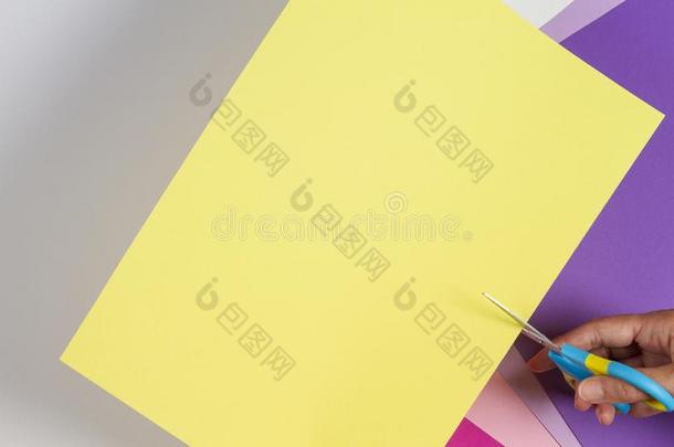 手和剪刀锋利的纸关于黄色的颜色纸