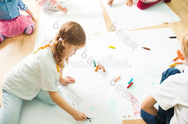 孩子们绘画和用彩色蜡笔画向一木制的地面