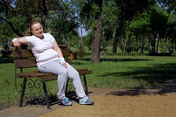 肥的女孩一次向长凳,疲倦的后的锻炼采用公园,缺乏关于