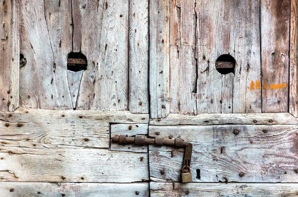 老的织地粗糙的风化的木制的门和挂锁.蹩脚货和凹凸不平的