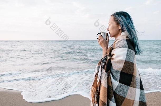 女人令人轻松的和杯子关于喝向海海岸.