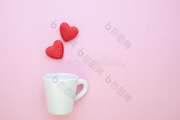 一白色的杯子和波尔卡舞点红色的心向粉红色的背景.复制品