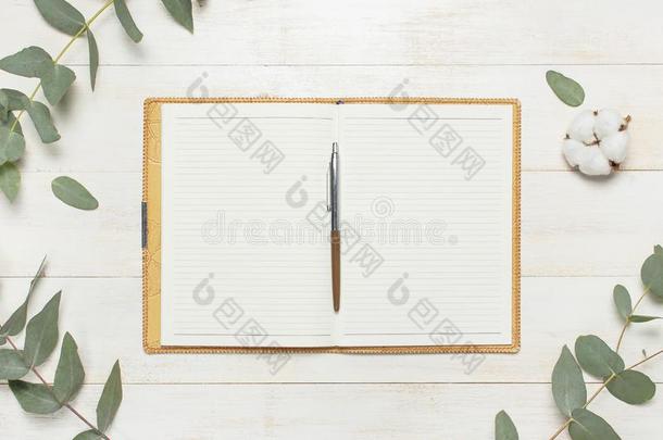 敞开的笔记簿和空白的页,笔,桉树细枝和棉