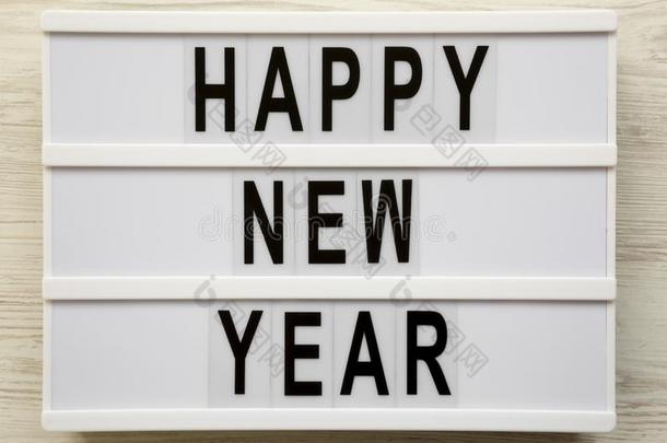`幸福的新的年`字向灯箱越过白色的木制的表面,向