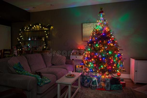 圣诞节树和礼物在下面它和甜饼干和奶左边的出局