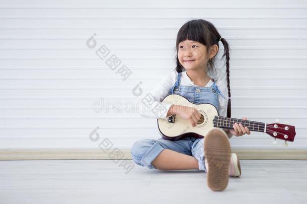 小的亚洲人女孩一次演奏夏威夷的四弦琴向白色的背景winter冬天
