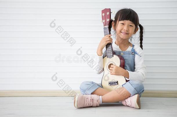 小的亚洲人女孩一次演奏夏威夷的四弦琴向白色的背景winter冬天