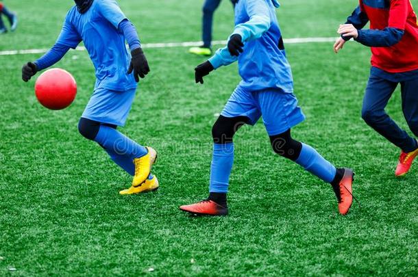 两个年幼的足球运动员采用红色的和蓝色运动装runn采用g,点滴留下