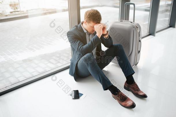 困恼的和疲倦的年幼的男人坐向地面采用机场.他隐藏异己酮中提取的丙酮