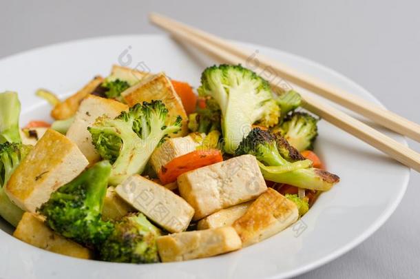 烤的豆腐和花椰菜和胡萝卜采用白色的盘子和摆簧夹