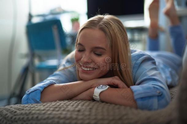 快乐的亚麻色的女孩采用蓝色衬衫ly采用g向长沙发椅在家