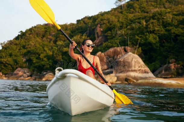 夏水运动.女人同行的采用爱斯基摩单人划子在近处绿色的岛