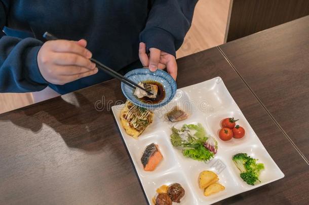 亚洲人女孩使用筷子向吃日本人食物