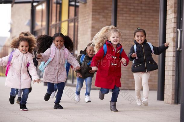 幸福的年幼的学校女儿使人疲乏的外套和运送的学校bags英语字母表的第18个字母