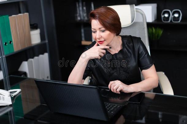 时髦的女人工作的和便携式电脑和电话采用办公室