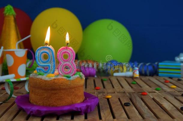 生日98蛋糕和蜡烛向乡村的木制的表和后面