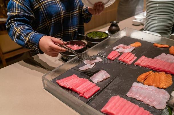 年幼的女孩挑选生鱼片采用指已提到的人自助餐