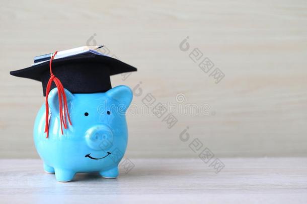 毕业帽子向蓝色小猪银行向木制的背景,节约英语字母表的第13个字母