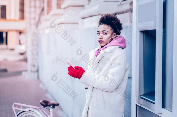 漂亮的国际的女人起立在近处现金机器