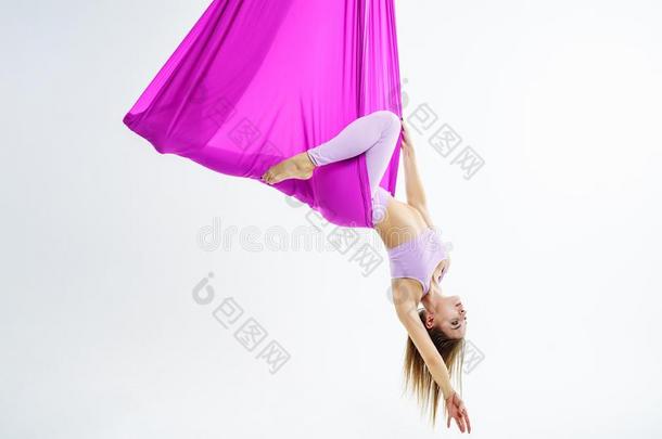 年幼的美丽的瑜珈修行者女人做空气的<strong>瑜伽</strong>练习采用<strong>紫色</strong>的