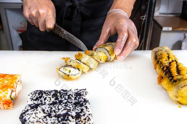 特写镜头关于厨师手旋转的在上面寿司切进入中一部分向衣物和装备