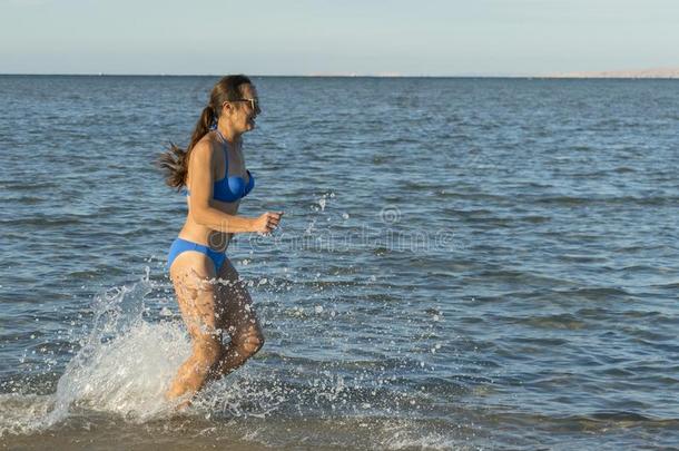 一年幼的黑头发的妇女女人或女孩使人疲乏的一比基尼式游泳衣跑步通过