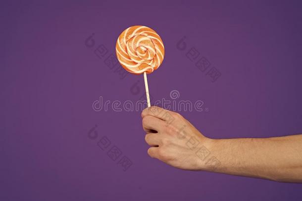 棒棒糖采用手向紫罗兰背景.糖果向粘贴向紫色的