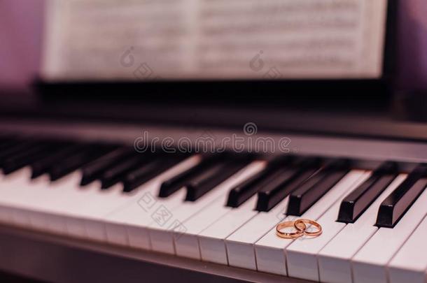 两个金色的婚礼戒指向钢琴调
