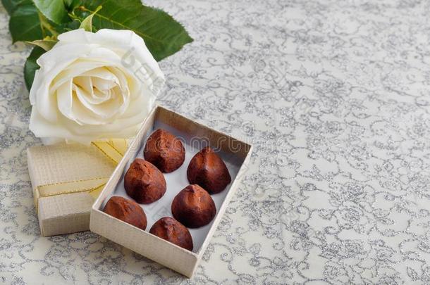 美丽的白色的玫瑰和金色的赠品盒和巧克力块菌