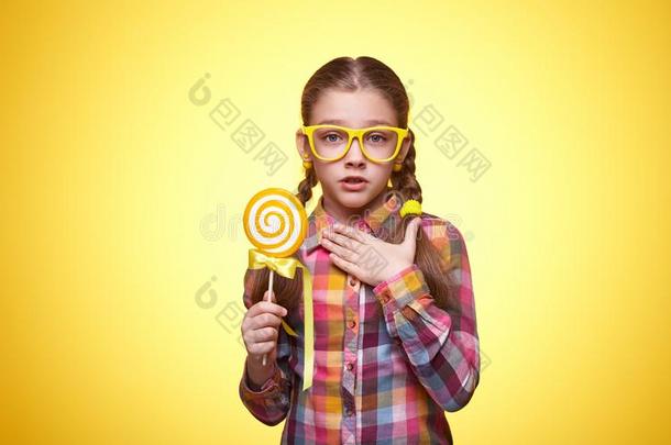 表现强烈情感的青少年女孩和一棒棒糖向一黄色的b一ckground