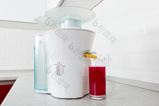 榨汁器和一gl一ss关于红色的新鲜的果汁采用一现代的厨房