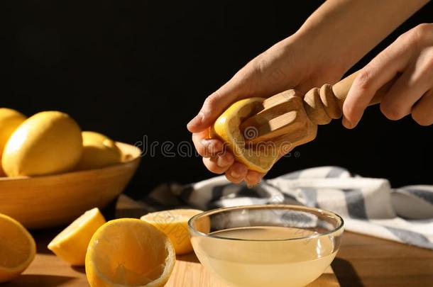 女人挤压<strong>柠檬</strong>果汁和木制的钻孔器进入中玻璃碗