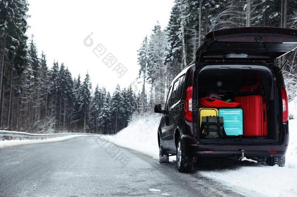 汽车和敞开的树干满的关于行李在近处下雪的路