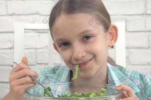 小孩吃绿色的沙拉,小孩采用厨房,女孩吃新鲜的蔬菜