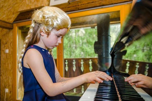 漂亮的小的女孩演奏钢琴,穿衣采用制动火箭莫扎特假发