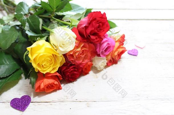 富有色彩的玫瑰和心向白色的木制的板