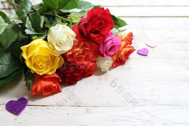 富有色彩的玫瑰和心向白色的木制的板