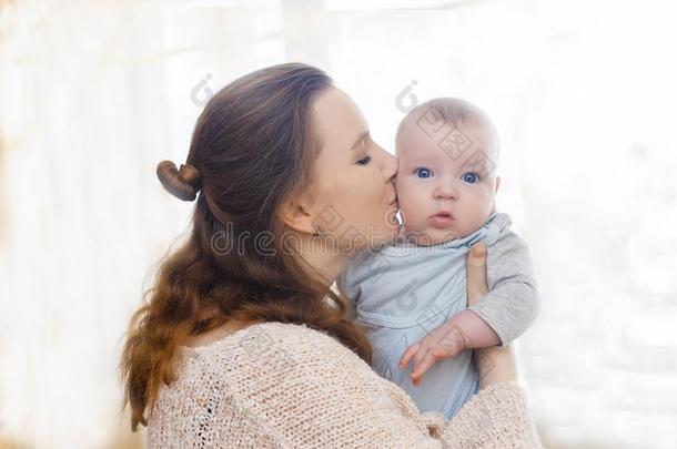 温和的照片关于母亲和婴儿.妈妈吻她儿子向指已提到的人脸颊