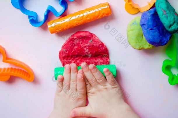 小孩手演奏和富有色彩的黏土.自家制的塑料制品