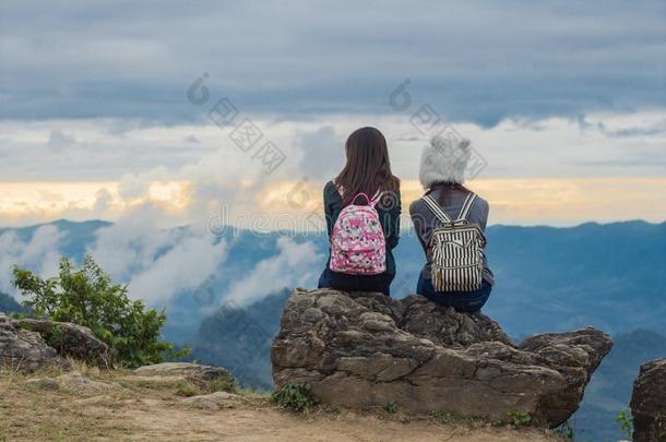 两个女儿坐向一岩石有样子的e一ch别的,蓝色天和云