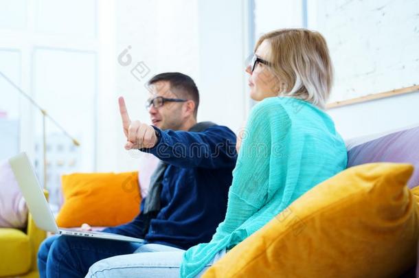 男人和女人坐向指已提到的人长沙发椅,闲谈和使用一桌面commerce商业