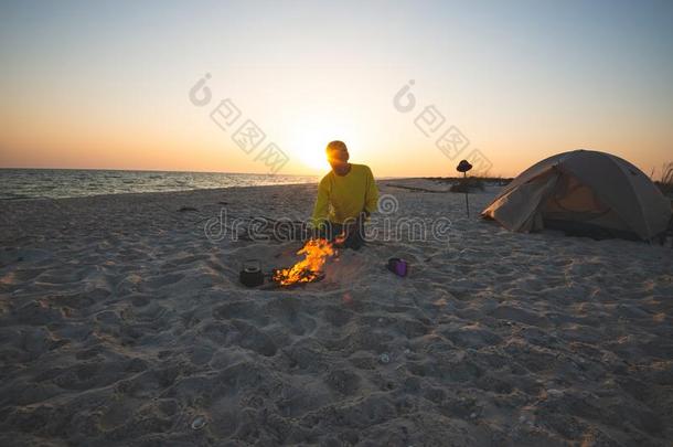 探险家坐紧接在后的向燃烧的营火向指已提到的人海滩