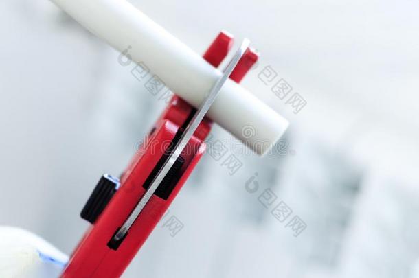 男人和红色的剪刀将切开小管为暖气装置,或水.多质的