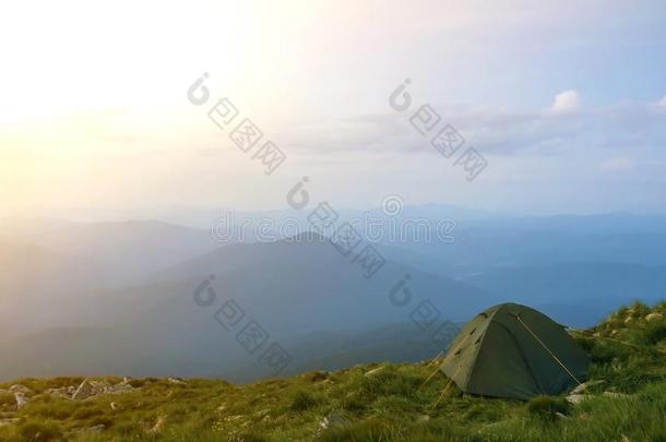 夏野营采用mounta采用s在黎明.旅行者帐篷向圆形的草