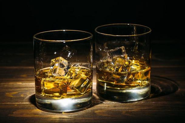 两个眼镜关于扑灭威士忌酒或白兰地酒的一种和冰立方形的东西向黑暗的令马停住的声音