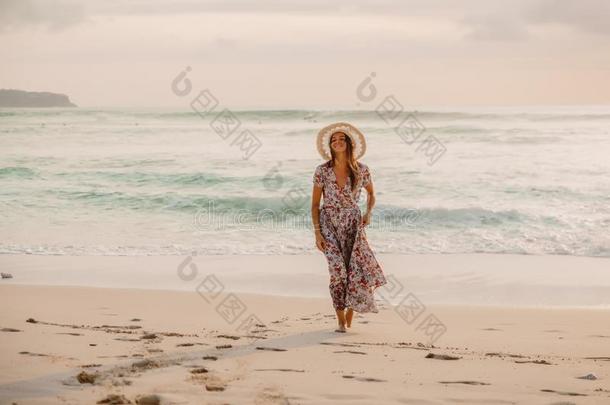 有魅力的女人采用夏衣服向海滩在日落或日出.