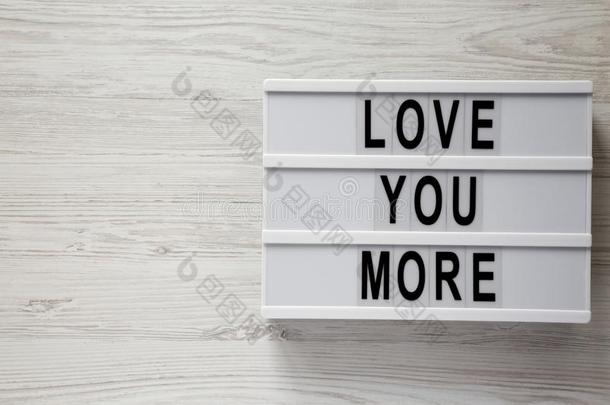 灯箱和文本`爱你更`向一白色的木制的surf一ce.V一